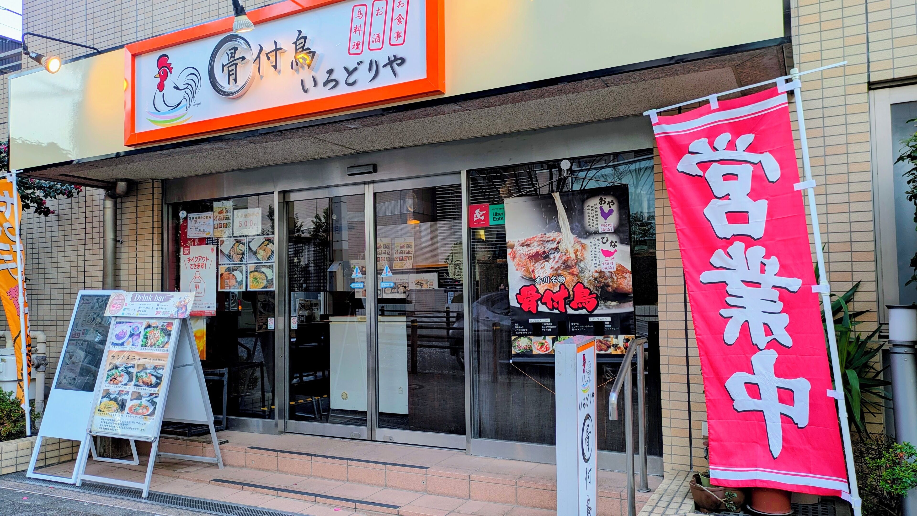 Un restaurant qui se distingue par une grande enseigne rouge et un panneau affichant le menu à l’extérieur.