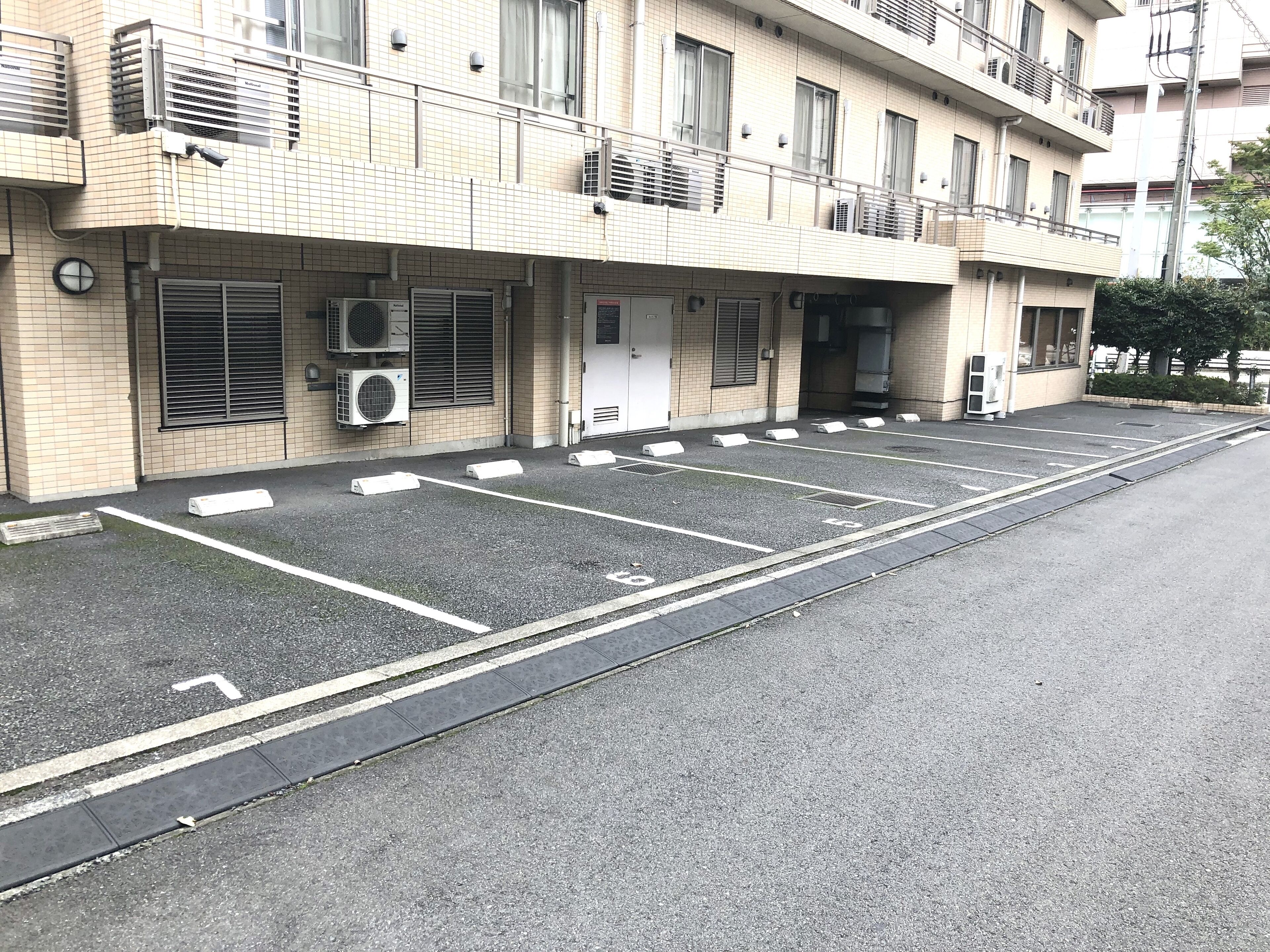 Ein mehrgeschossiges Gebäude mit Parkplatz davor.