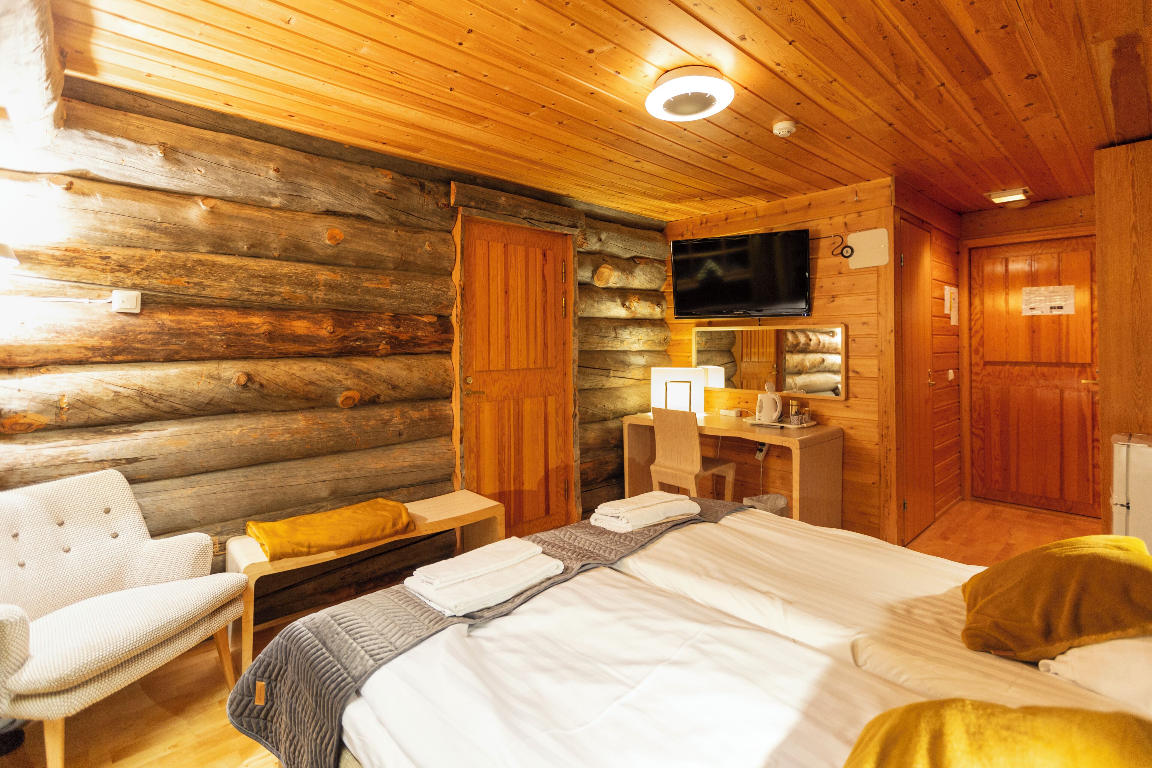 Een blokhutkamer met een bed, een stoel, een bureau en een televisie.