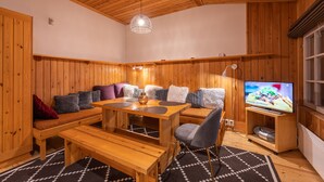 A cozy wooden room with a sofa, a dining table, and a TV. - Kuukkeli Apartments Tokka (Saariselka)