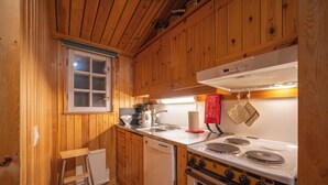 A wooden-paneled kitchen with a white stove, a dishwasher, and a window. - Kuukkeli Apartments Tokka (Saariselka)
