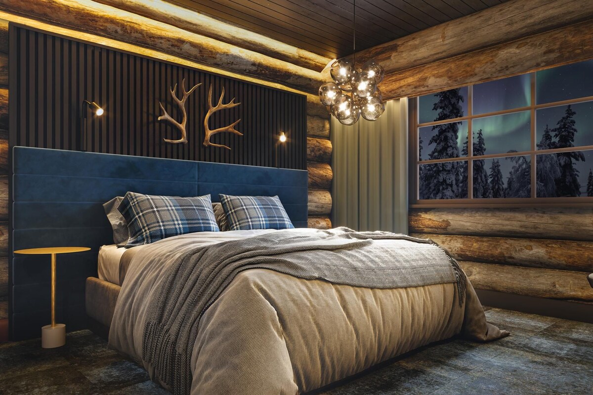 A bedroom with a log wall, a bed with a blue headboard, and a window with a view of trees.