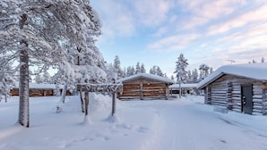 Un albergue cubierto de nieve con cabañas de madera, una valla de madera y árboles cargados de nieve.