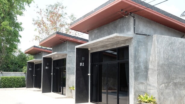 A row of modern, numbered hotel rooms with large glass doors and a concrete exterior. - Riad Resort (Aranyaprathet)