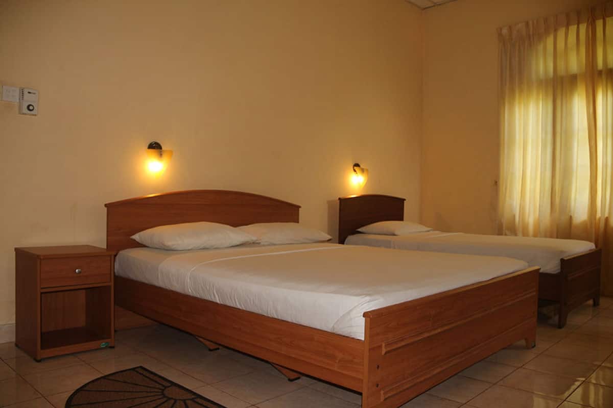 A room with two wooden beds, each with a nightstand and a wall-mounted light.