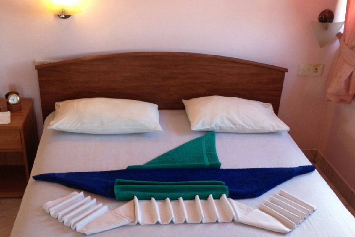 A neatly made bed with pillows and a folded towel.