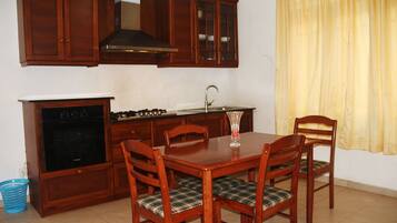 A kitchen with wooden cabinets, a stove, and a dining table with chairs.