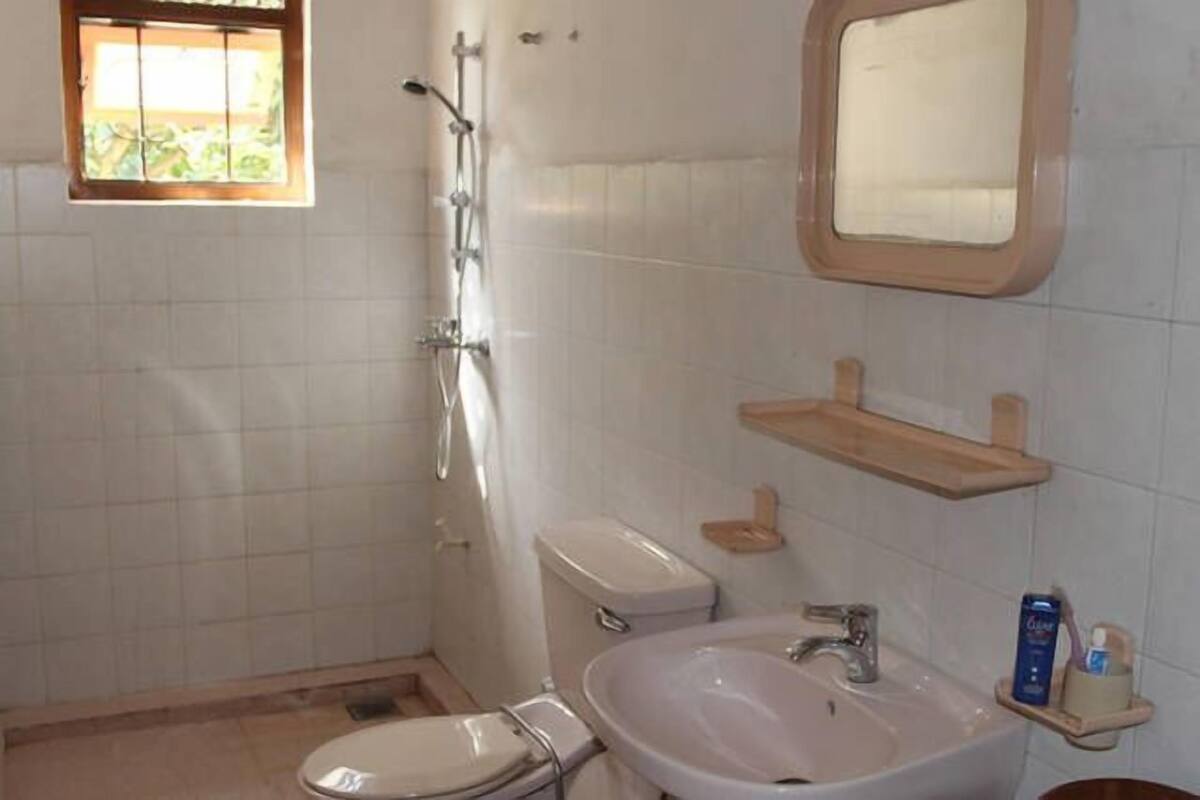 A bathroom with a toilet, sink, mirror, and shower.