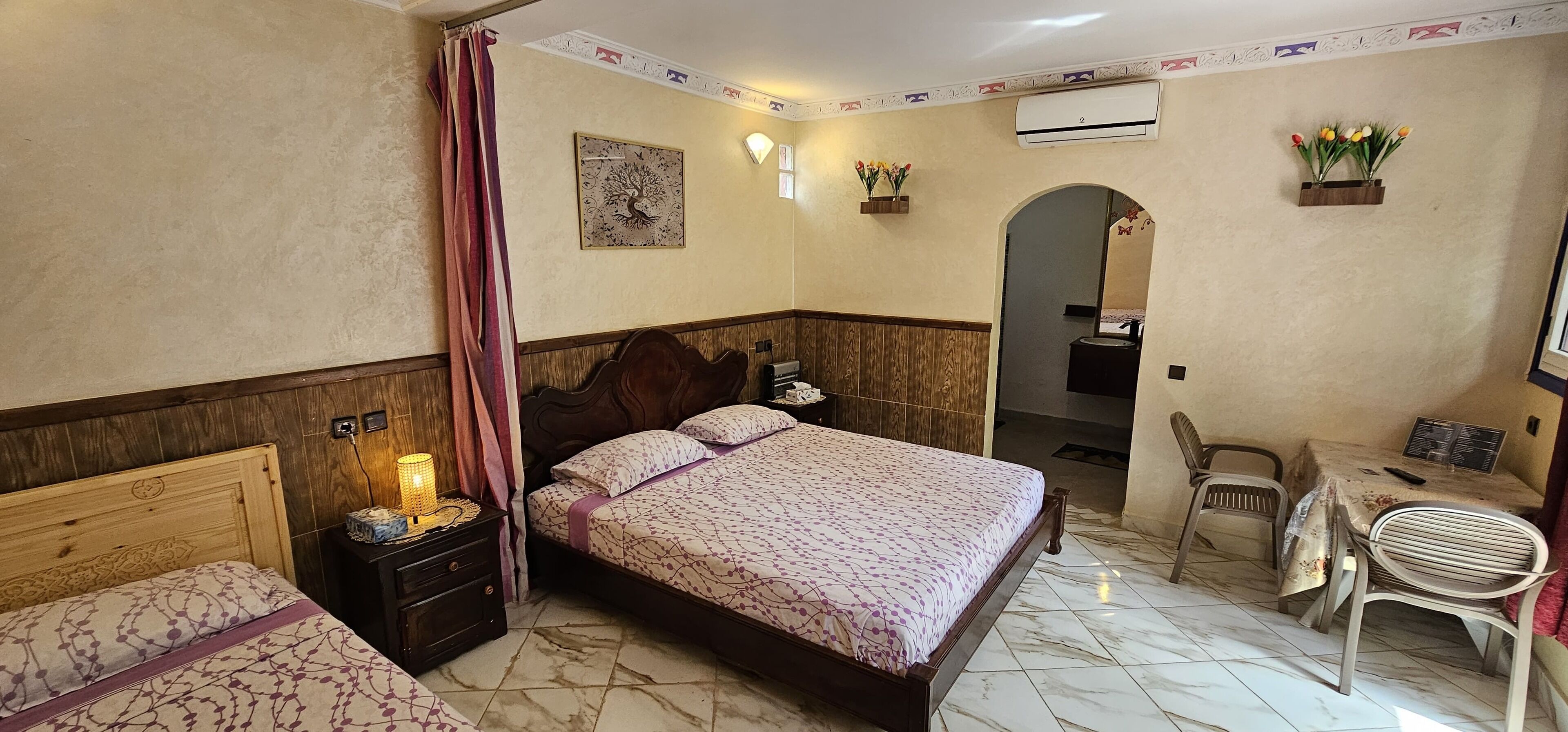 Un dormitorio con una cama grande, mesitas de noche, un escritorio y sillas.