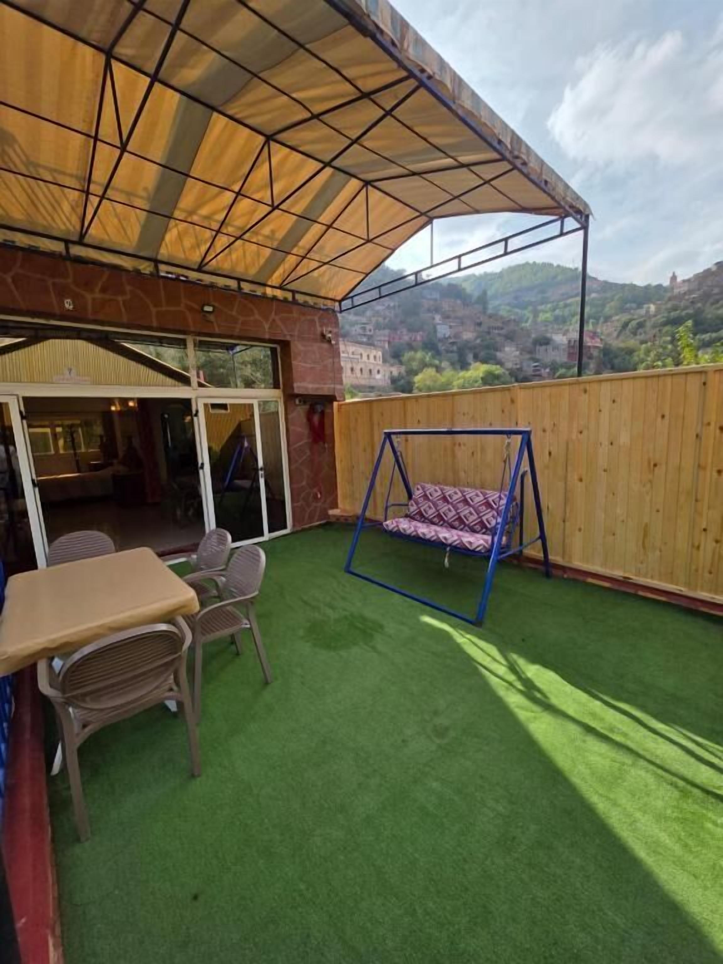 Un patio al aire libre con una hamaca, una mesa y sillas.