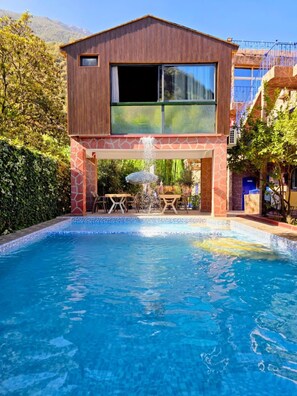 A modern two-story building with a swimming pool in front.