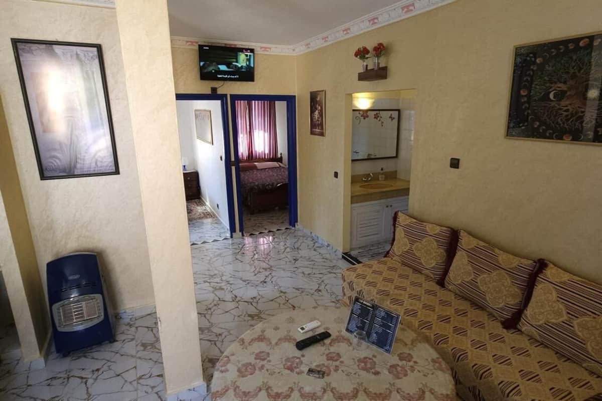 A living room with a sofa, a television, a mirror, and a door leading to another room.