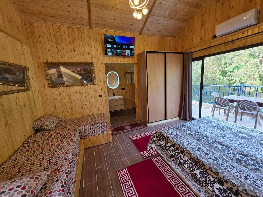 L’intérieur d’un chalet en bois comprend une télévision, un miroir, une salle de bain et un balcon avec des chaises.