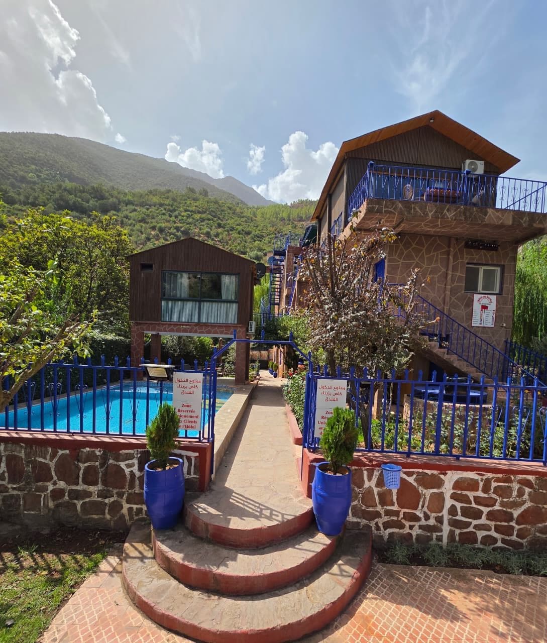 A hotel with a pool, stone walls, and a mountain backdrop.