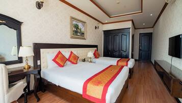 A hotel room with two beds, a desk, a chair, a TV, and a wardrobe.