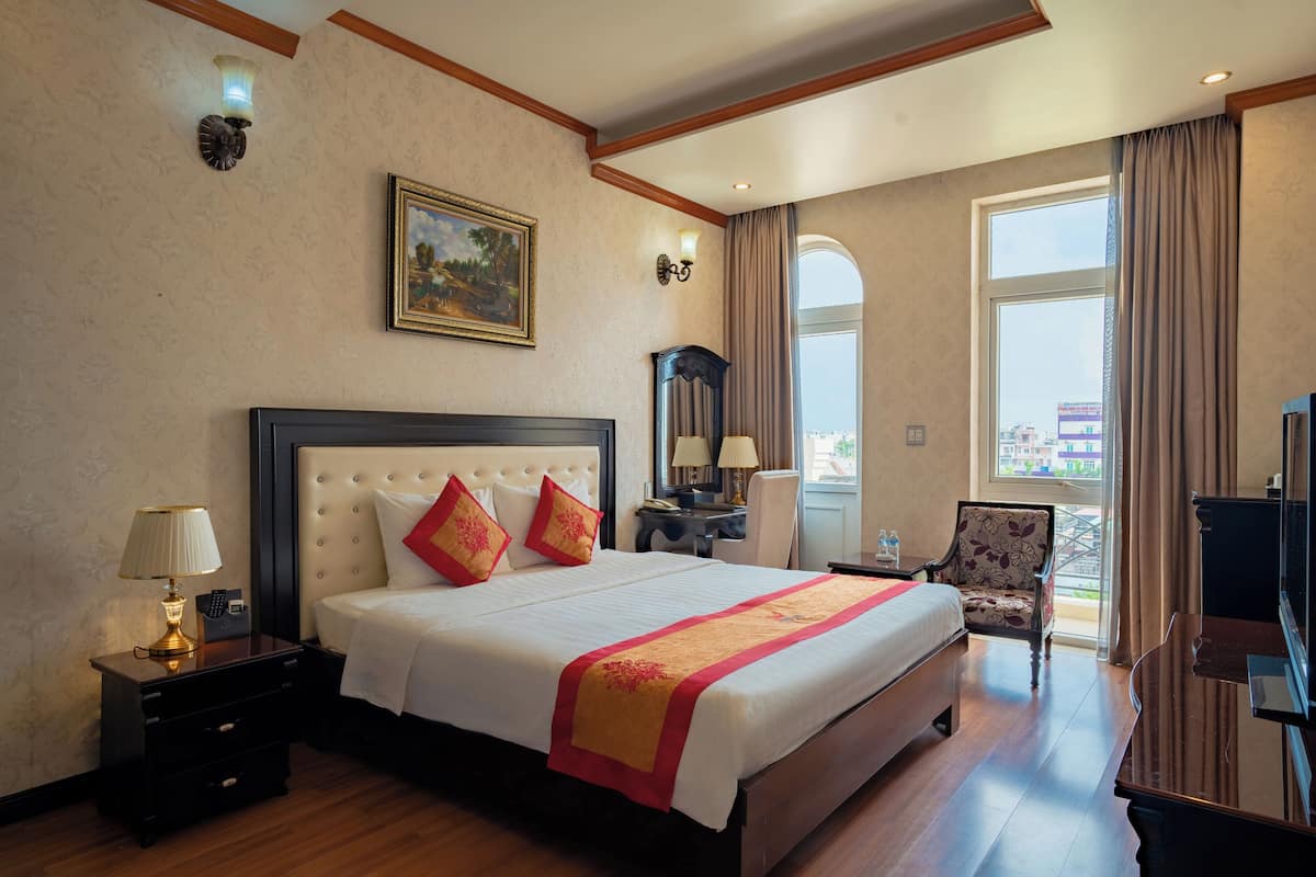 Ein Hotelzimmer mit einem großen Bett, einem Schreibtisch, einem Stuhl und einem Fernseher.