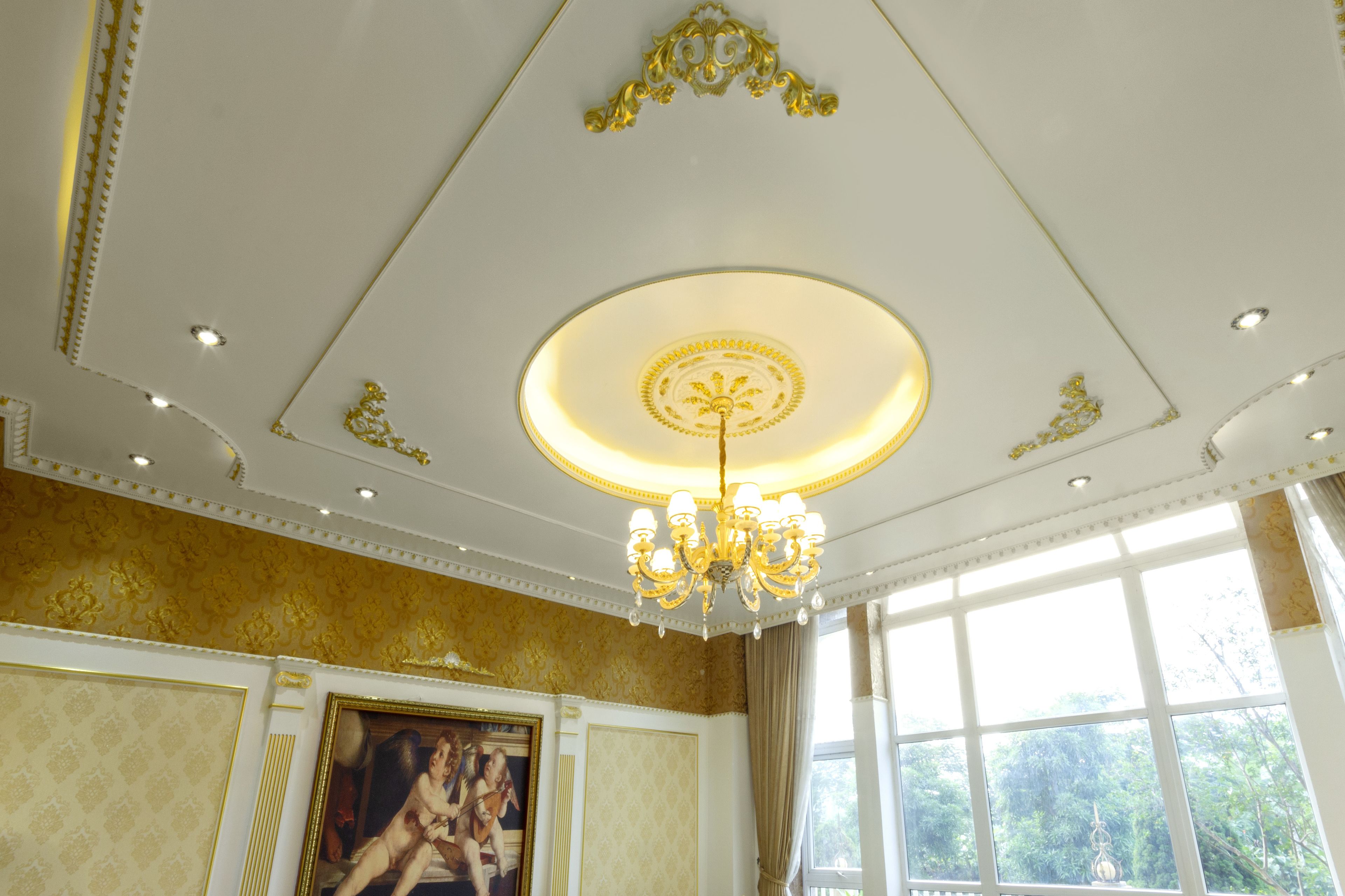 A room with a chandelier, a large window, and a painting on the wall.
