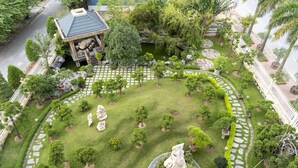 A well-maintained garden with a gazebo, stone pathways, and neatly trimmed bushes.