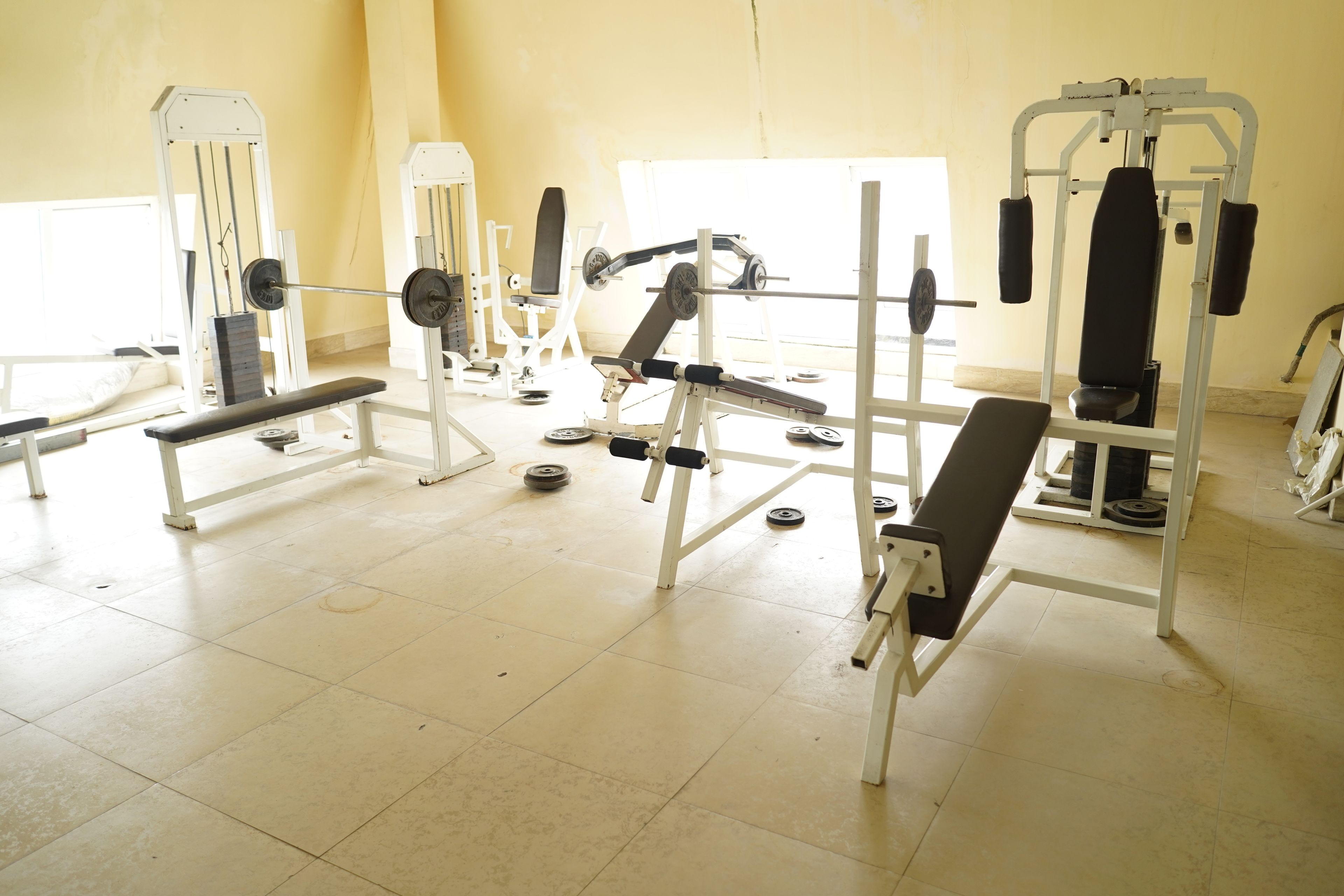 A gym with various exercise equipment including benches, weight machines, and free weights.