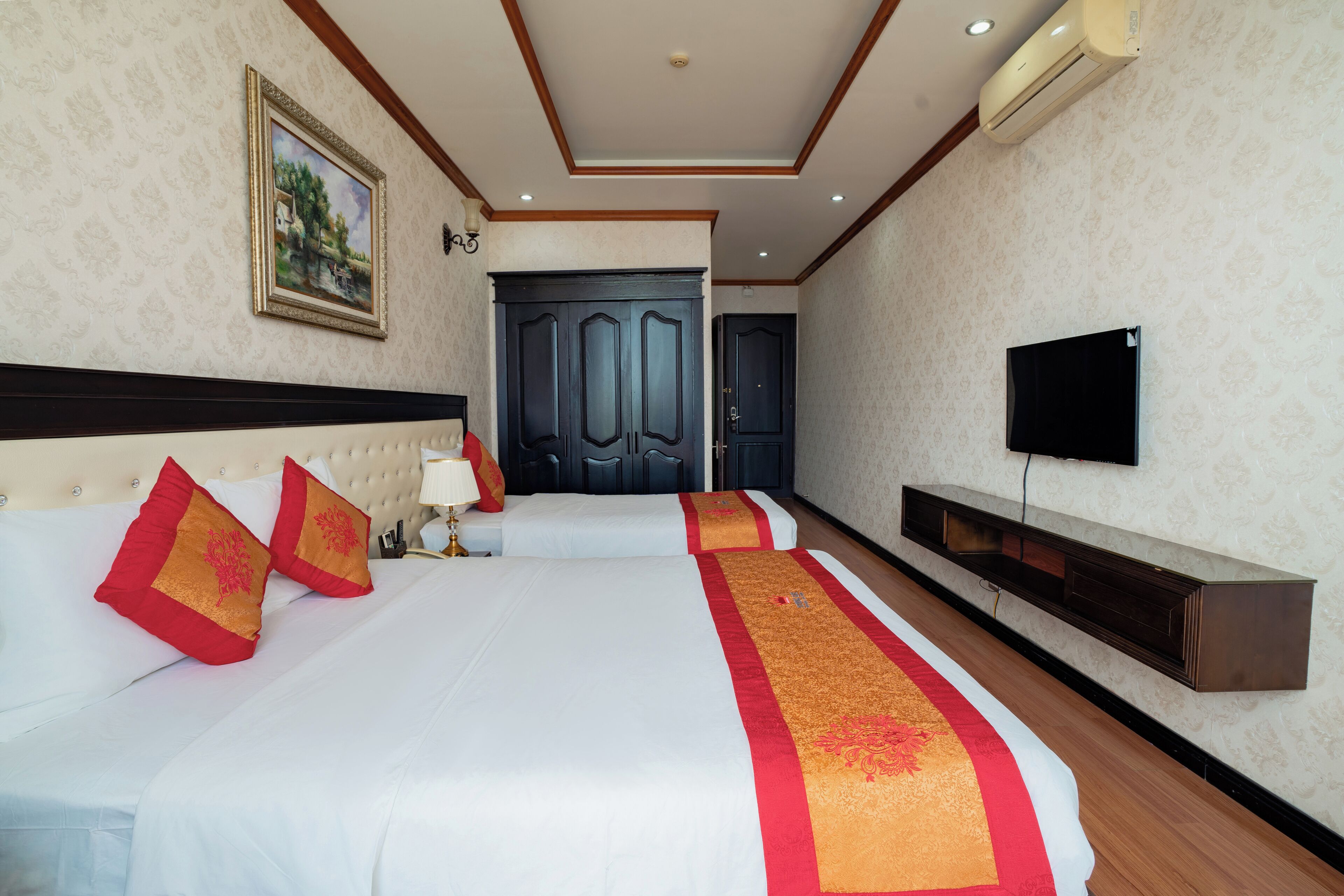 A hotel room with two beds, a TV, a wardrobe, and a painting on the wall.