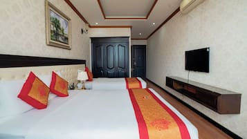 A hotel room with two beds, a TV, a wardrobe, and a painting on the wall.