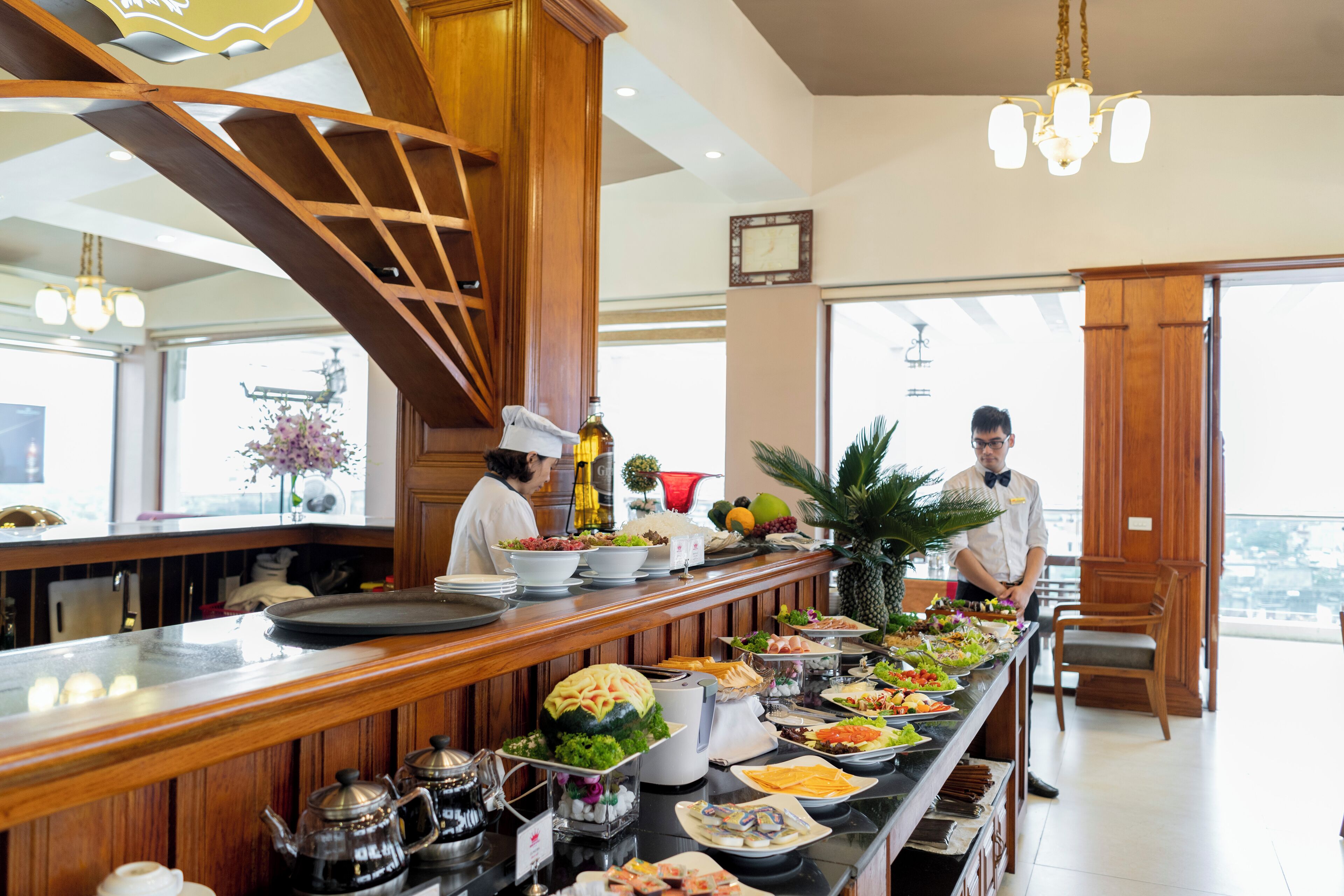 A buffet setup with various food items and a chef preparing food.