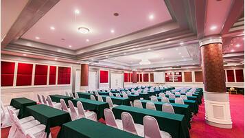 A conference room with rows of tables and chairs, a red carpet, and a pillar.