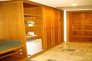 Un armario de madera con estantes, un refrigerador blanco y una puerta de madera.