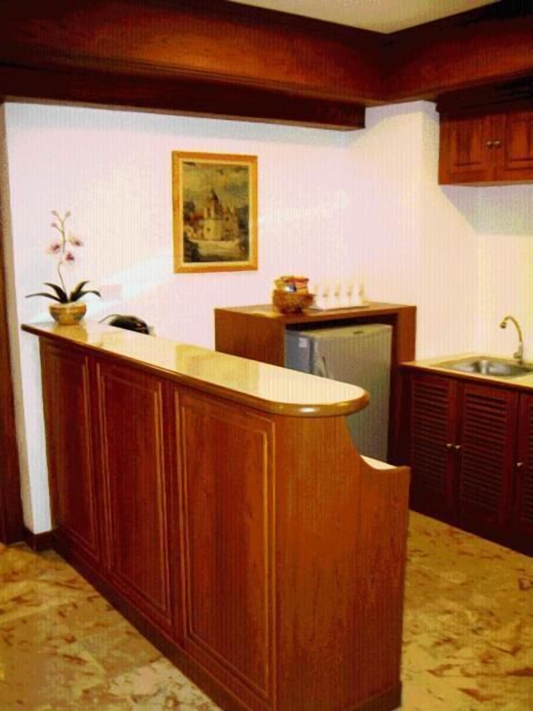 A kitchen with wooden cabinets, a built-in island, a refrigerator, and a sink.