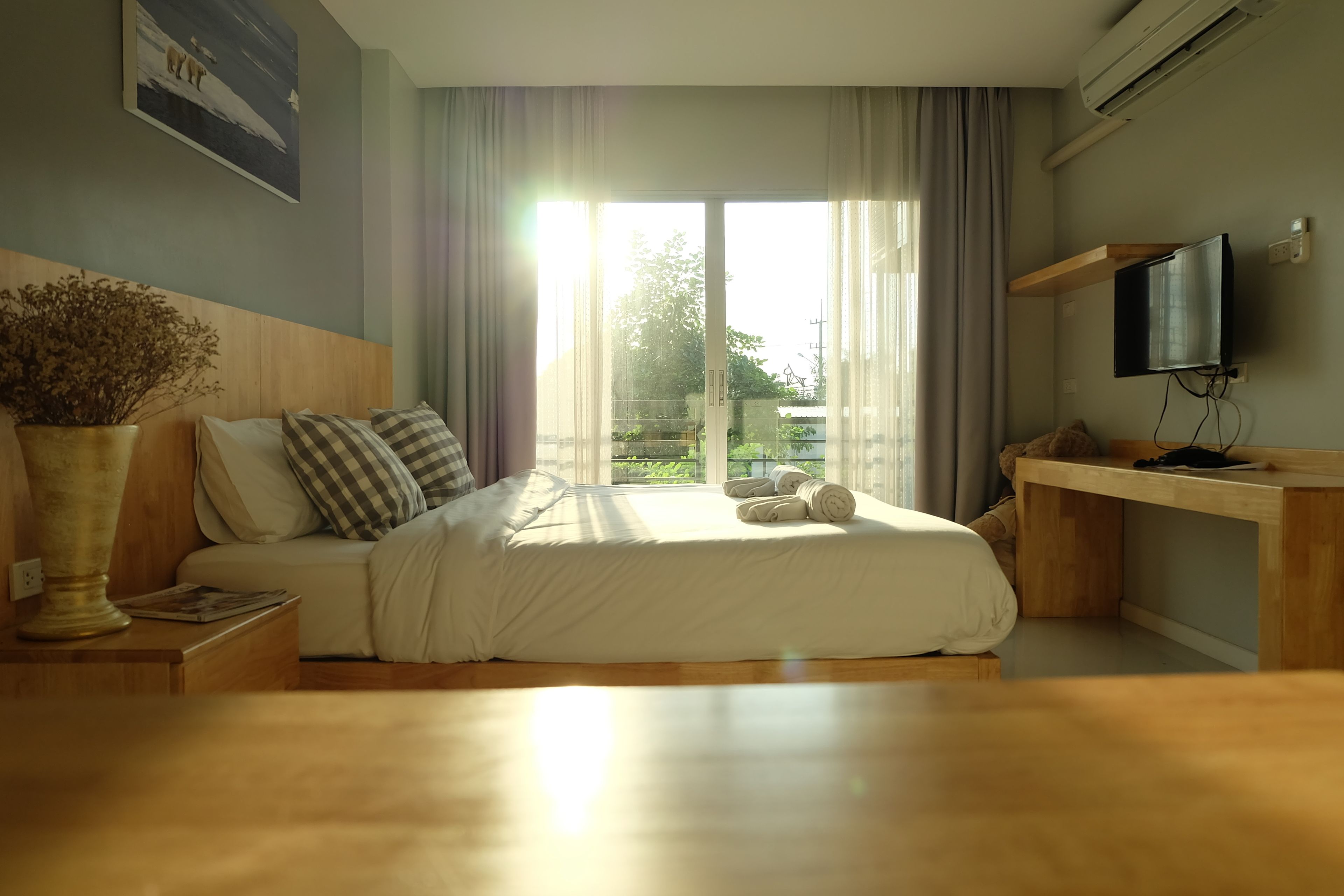 Une chambre à coucher avec un lit, une table de chevet et un téléviseur posé sur un meuble.