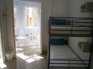 A room with bunk beds, a small table, and a chair near a window. - Casa Al Sur Terraza Hostel (Málaga)