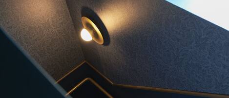 A staircase with a patterned wall and a light fixture on the wall.