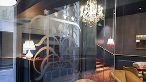 Een modern interieur met een glazen scheiding, een kroonluchter en een bank.