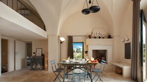 Un coin repas avec une table dressée pour quatre personnes, entourée de chaises, d’une cheminée et offrant une vue sur l’extérieur.