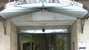 La entrada a un hotel con puerta de cristal y un letrero que dice 'Hotel Ciudad'.