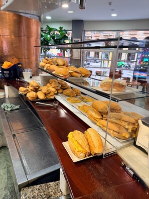 A buffet with various sandwiches and a bowl of oranges. - Hotel Gijon (Gijon)