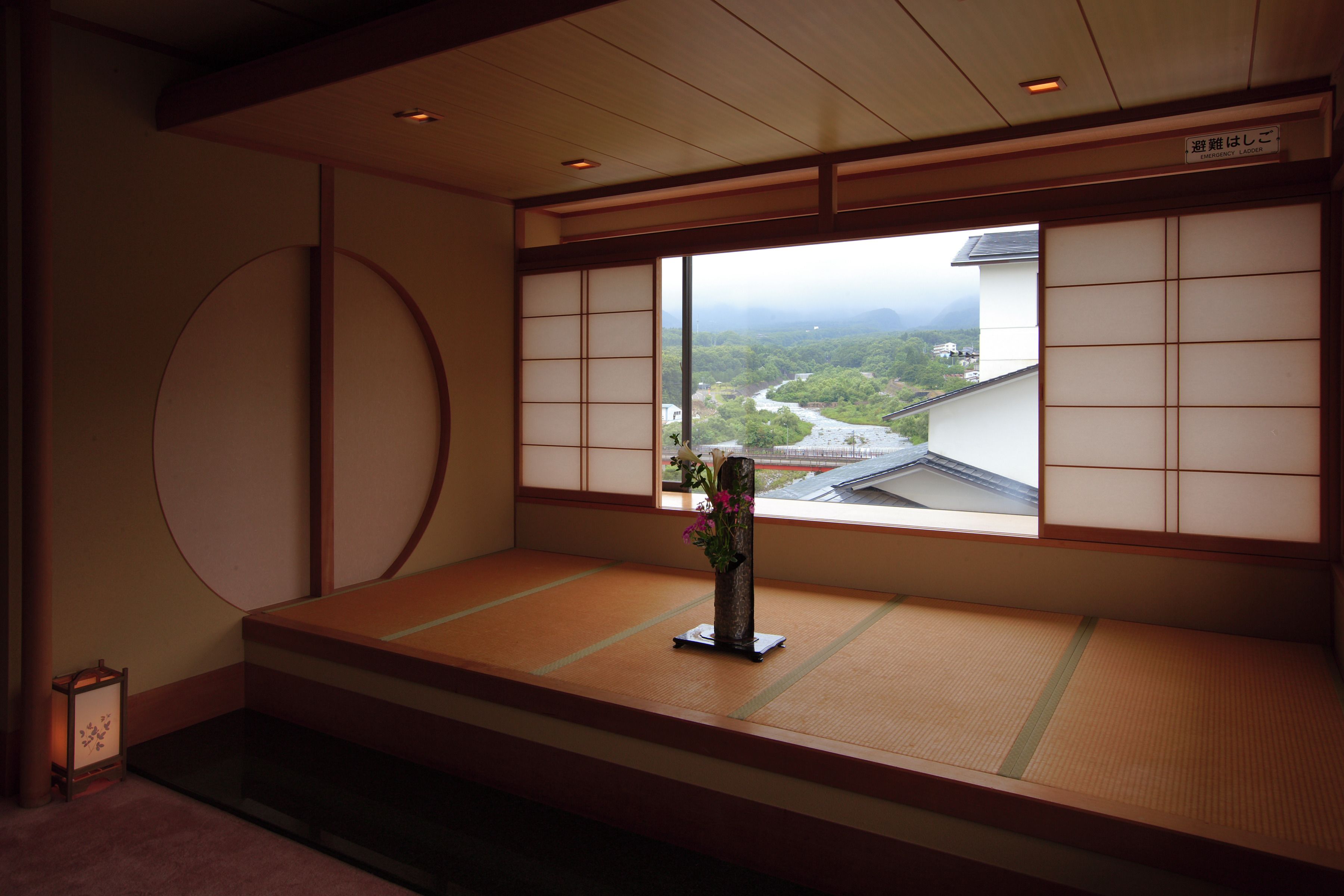 Una habitación con tatami que ofrece vista a un río y montañas.