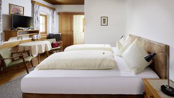 A hotel room with two beds, a TV, a desk with a chair, and a wooden ceiling.