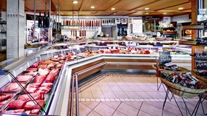Une boucherie où diverses sortes de viandes sont exposées dans des vitrines réfrigérées et sur des comptoirs.
