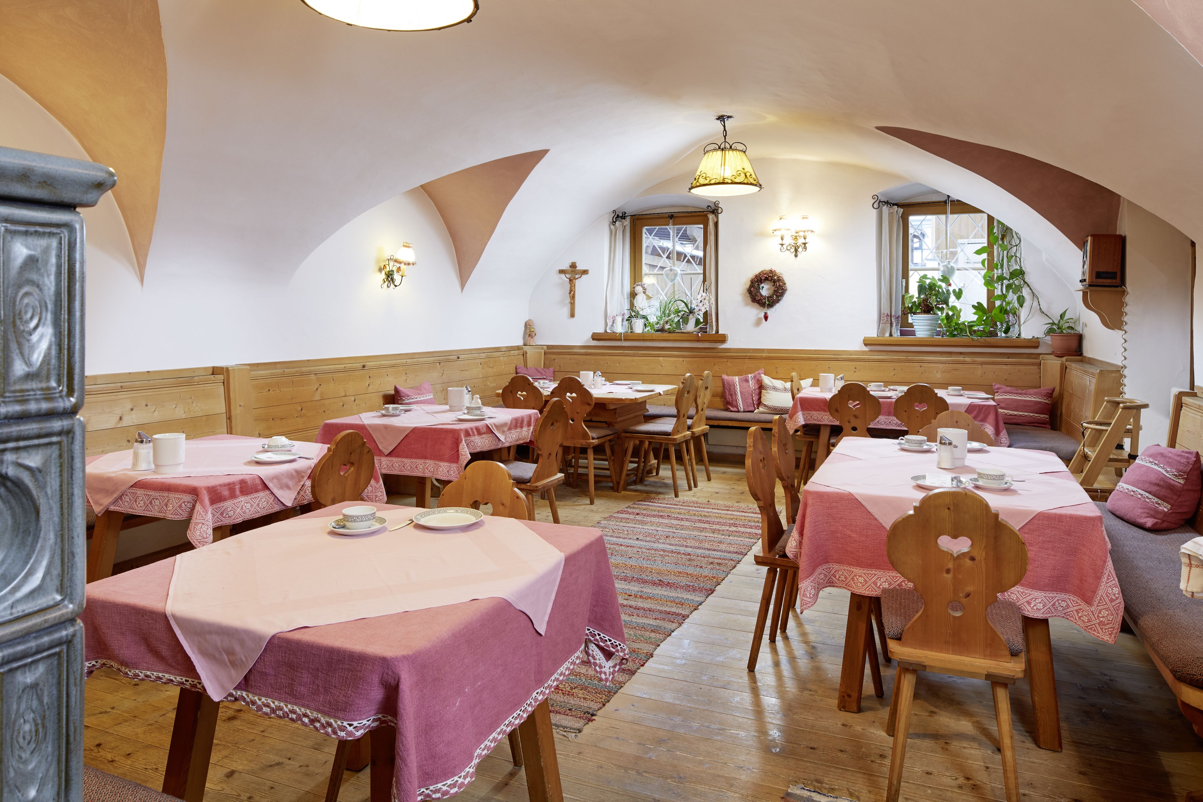 A dining area with tables set for four, wooden chairs, and a bench.