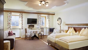 Une chambre d’hôtel avec un lit, un canapé, une télévision, une table et une chaise.