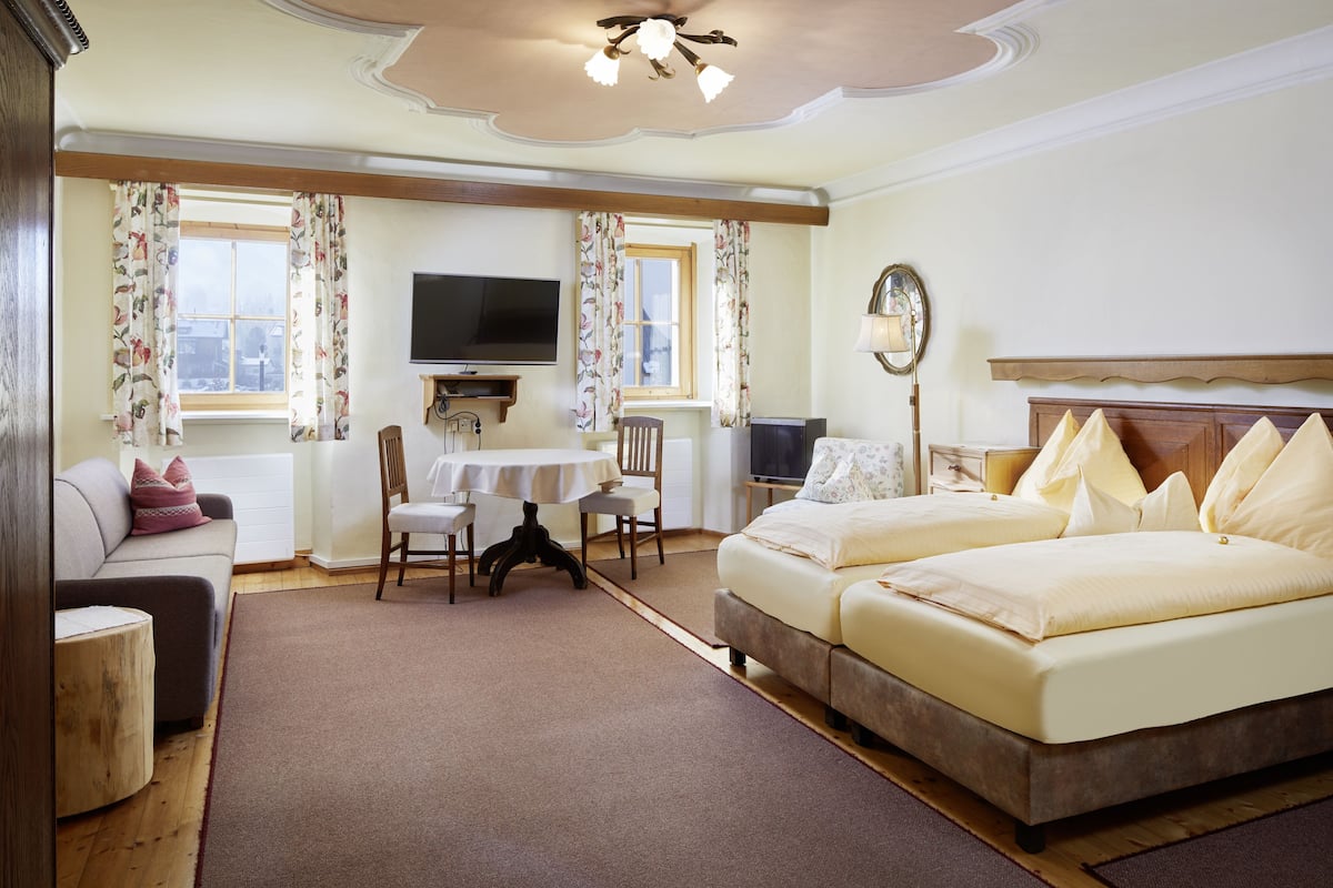 Habitación de hotel con cama, sofá, televisor, mesa y silla.