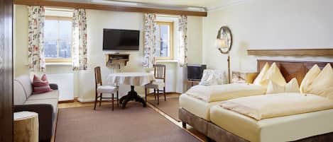 Habitación de hotel con cama, sofá, televisor, mesa y silla.