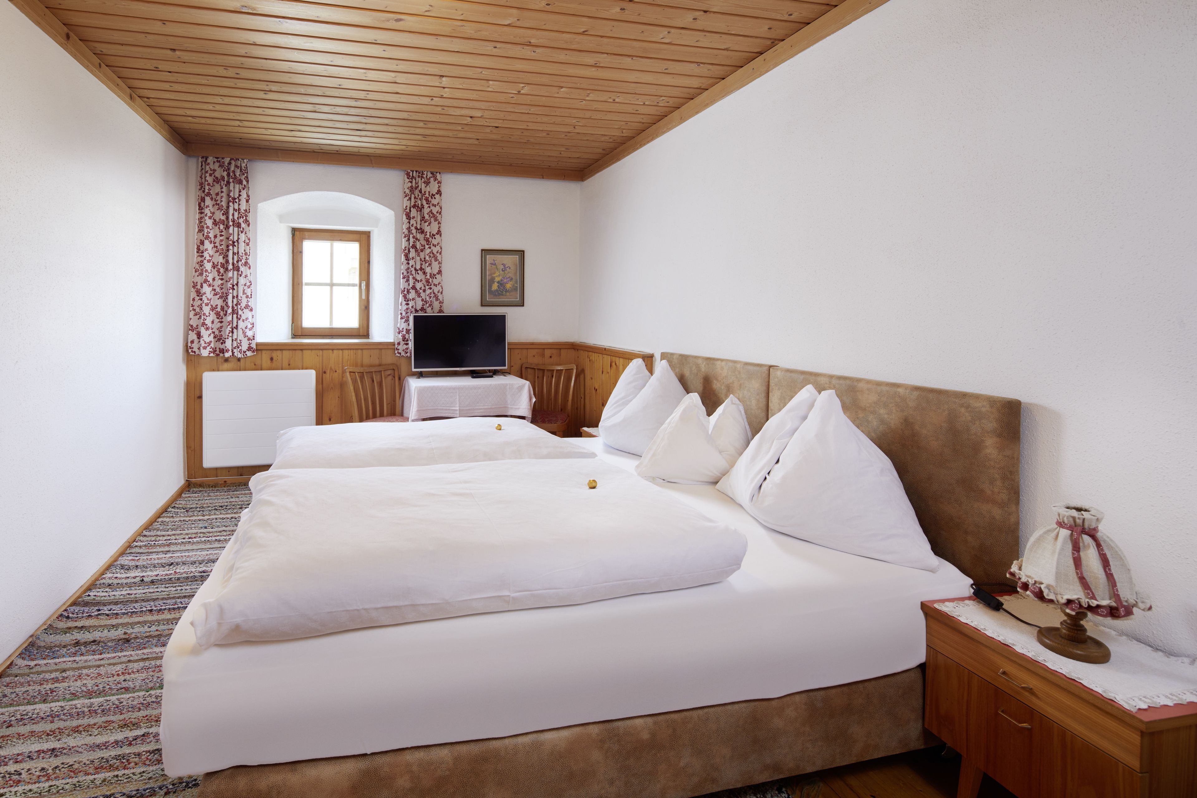 A hotel room with two beds, a television, a small table, and a lamp.