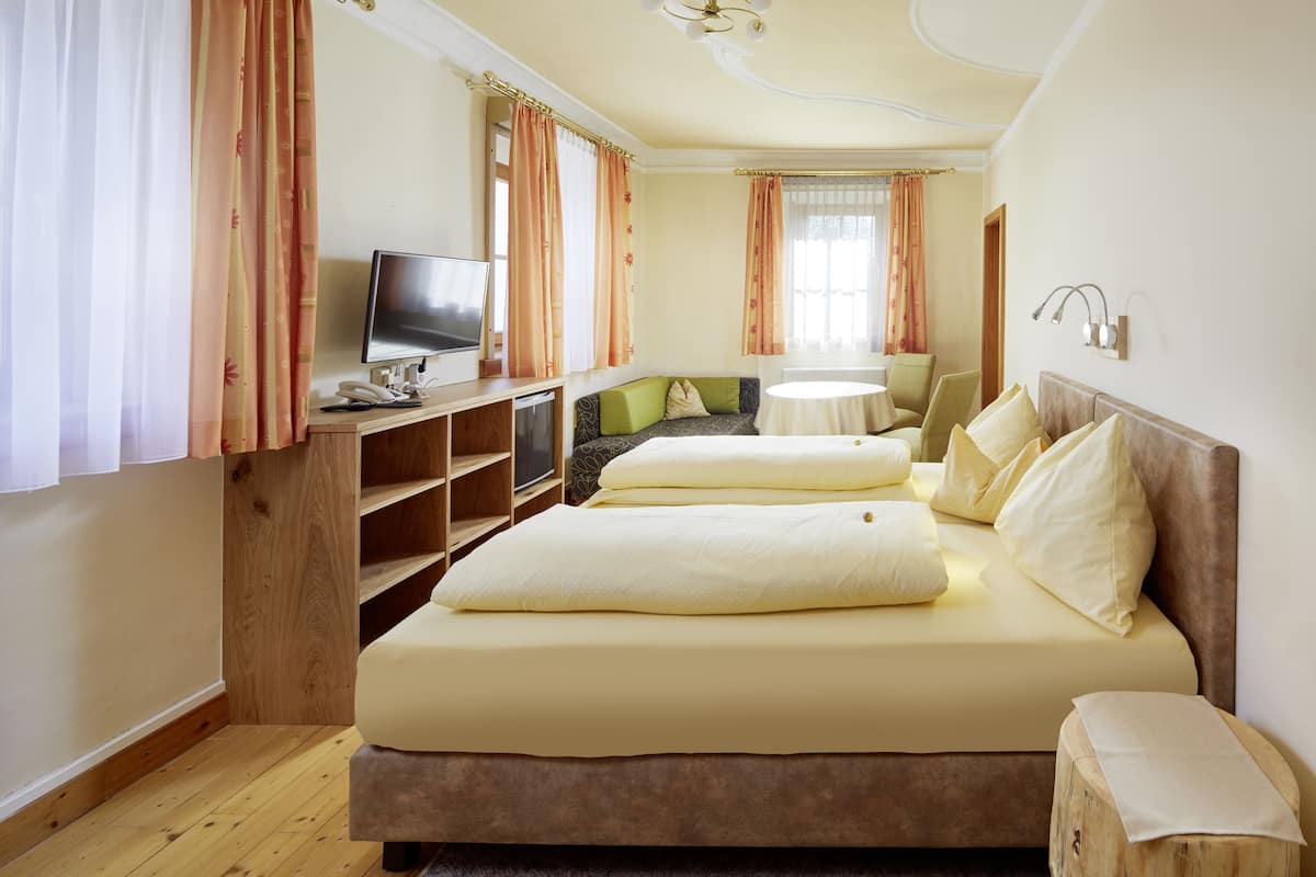 Habitación de hotel con cama doble, escritorio con computadora, televisor y una mesita.