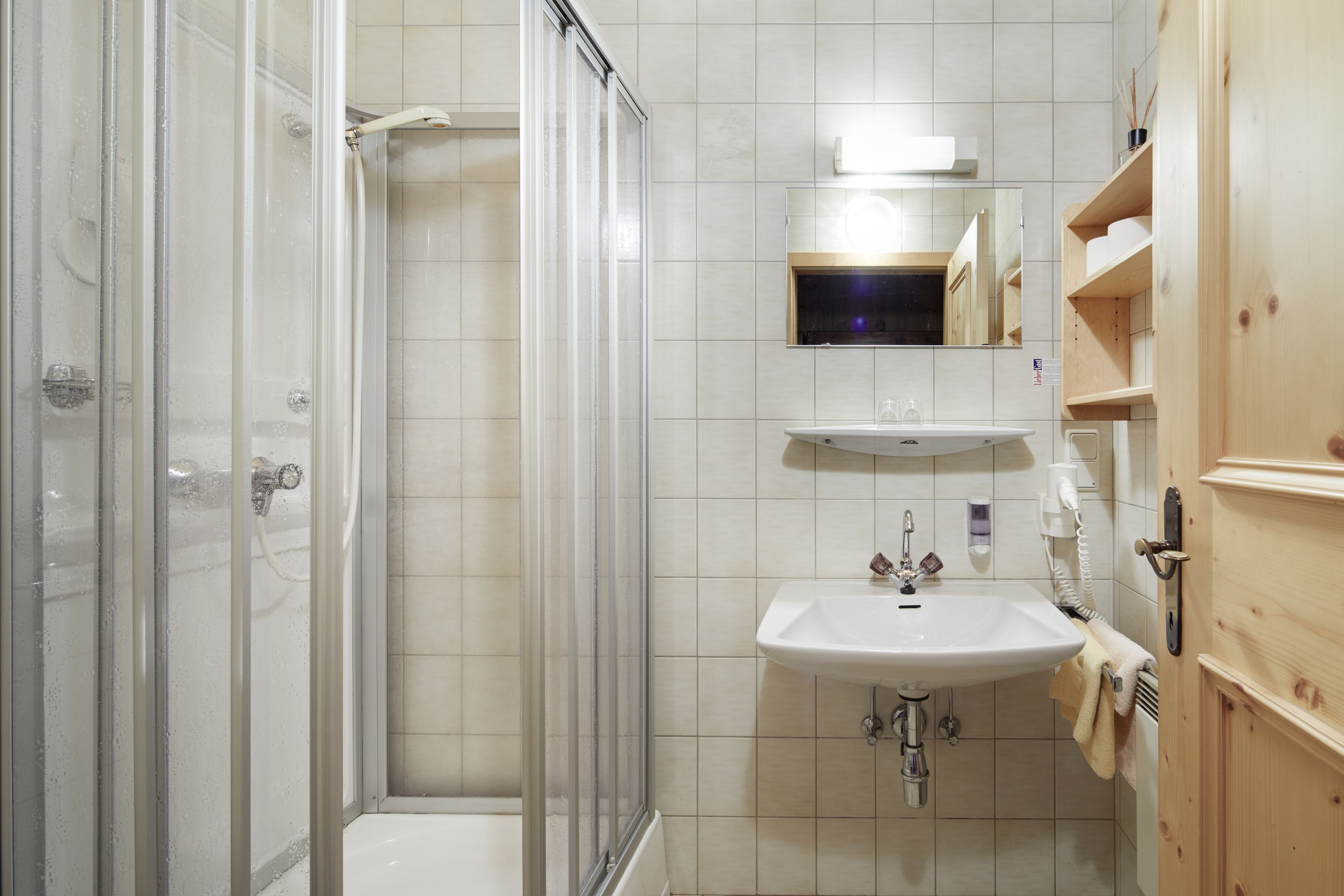 A bathroom with a glass-enclosed shower, a sink, and wooden cabinets.
