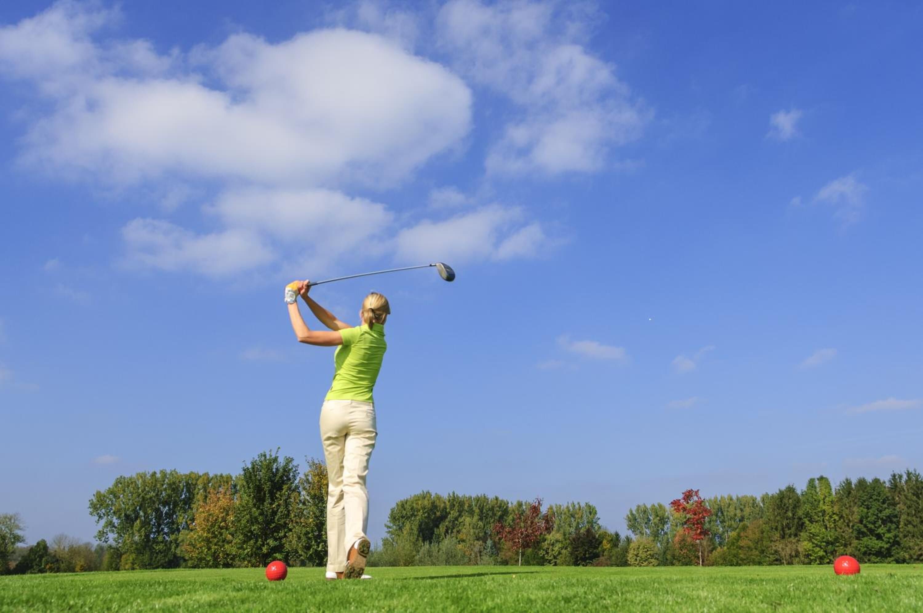 Una persona jugando al golf en un día soleado.