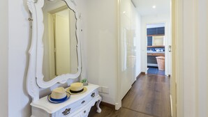 A hallway with a white vanity, a large mirror, and a door leading to a kitchen area. - Downtown Alegria B&B (Tavira)