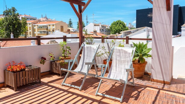 A rooftop terrace with potted plants, a drying rack, and a view of surrounding buildings. - Downtown Alegria B&B (Tavira)