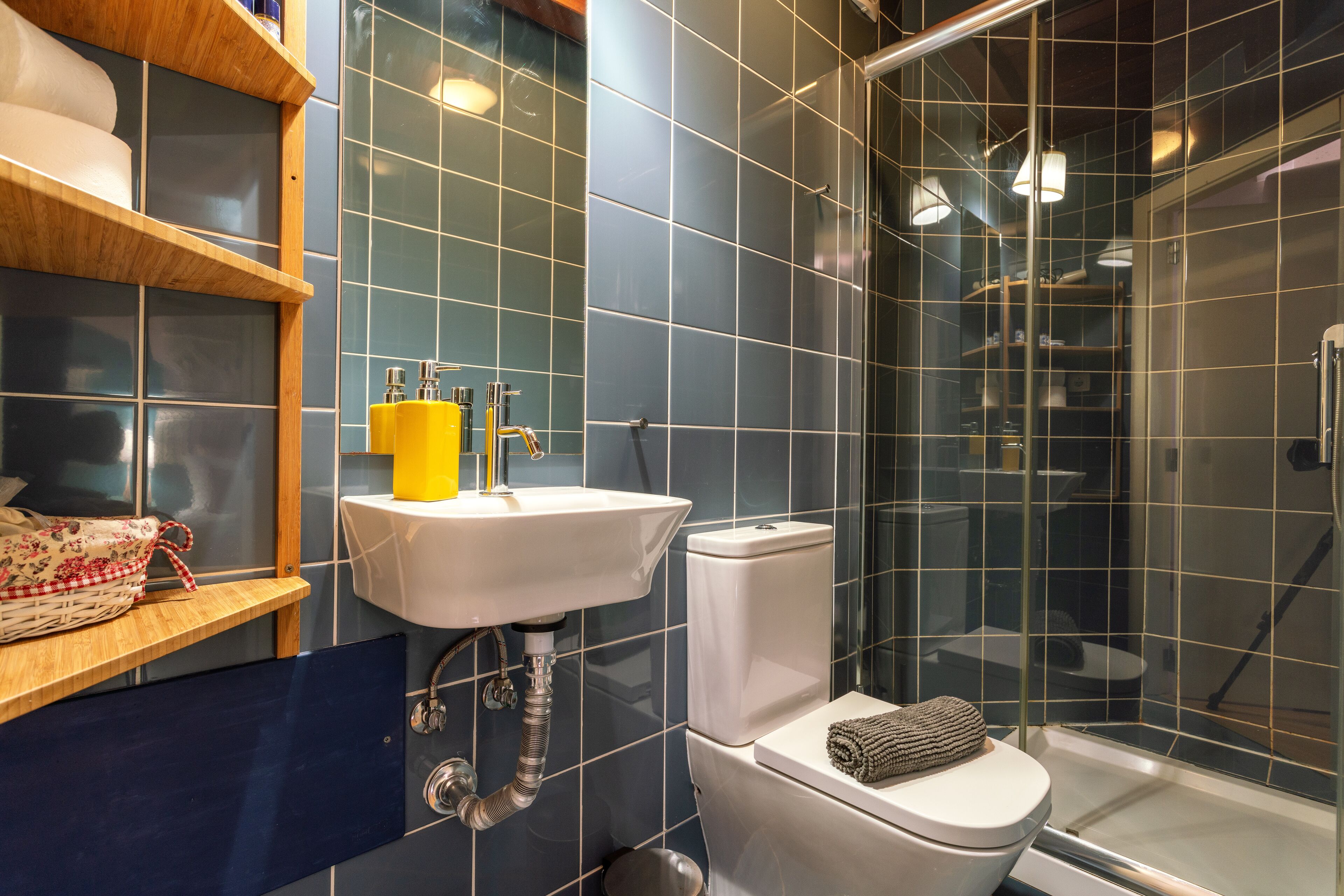 Un bagno moderno con cabina doccia in vetro, un lavandino bianco e un water con un asciugamano sopra.